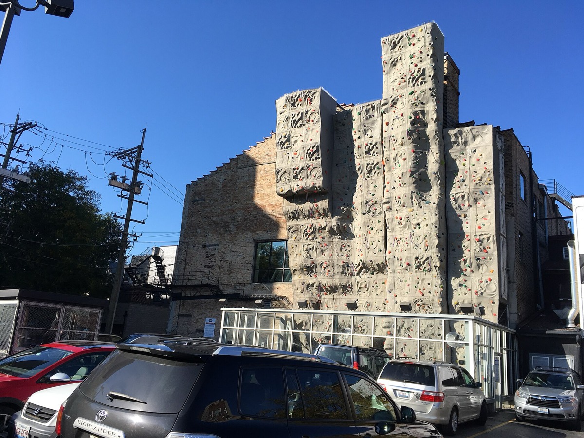 קיר טיפוס מלאכותי ובו אחיזות צבעוניות במסלולים שונים; אין מטפס בתצלום