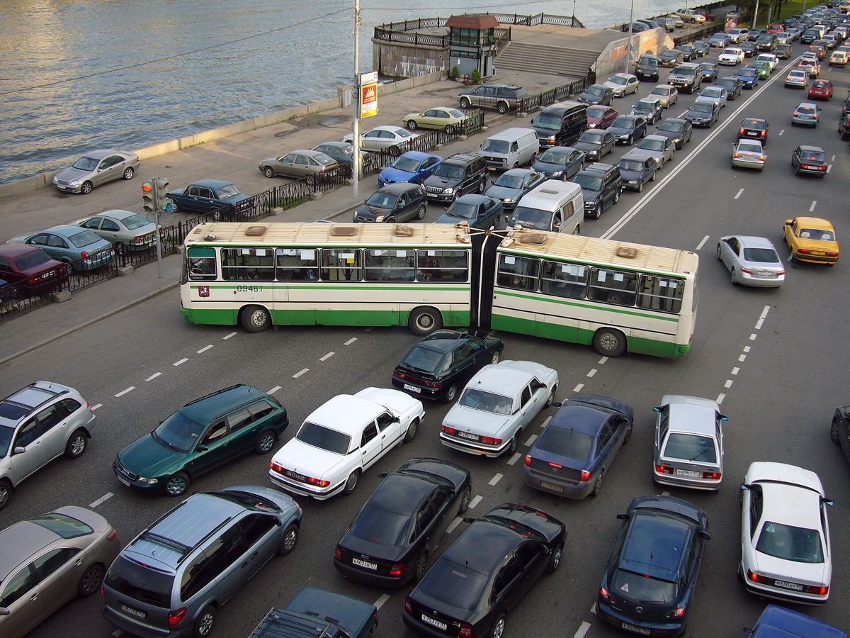 תנועה צפופה של מכוניות ואוטובוס מפרקי בצומת עירוני, מבט מלמעלה